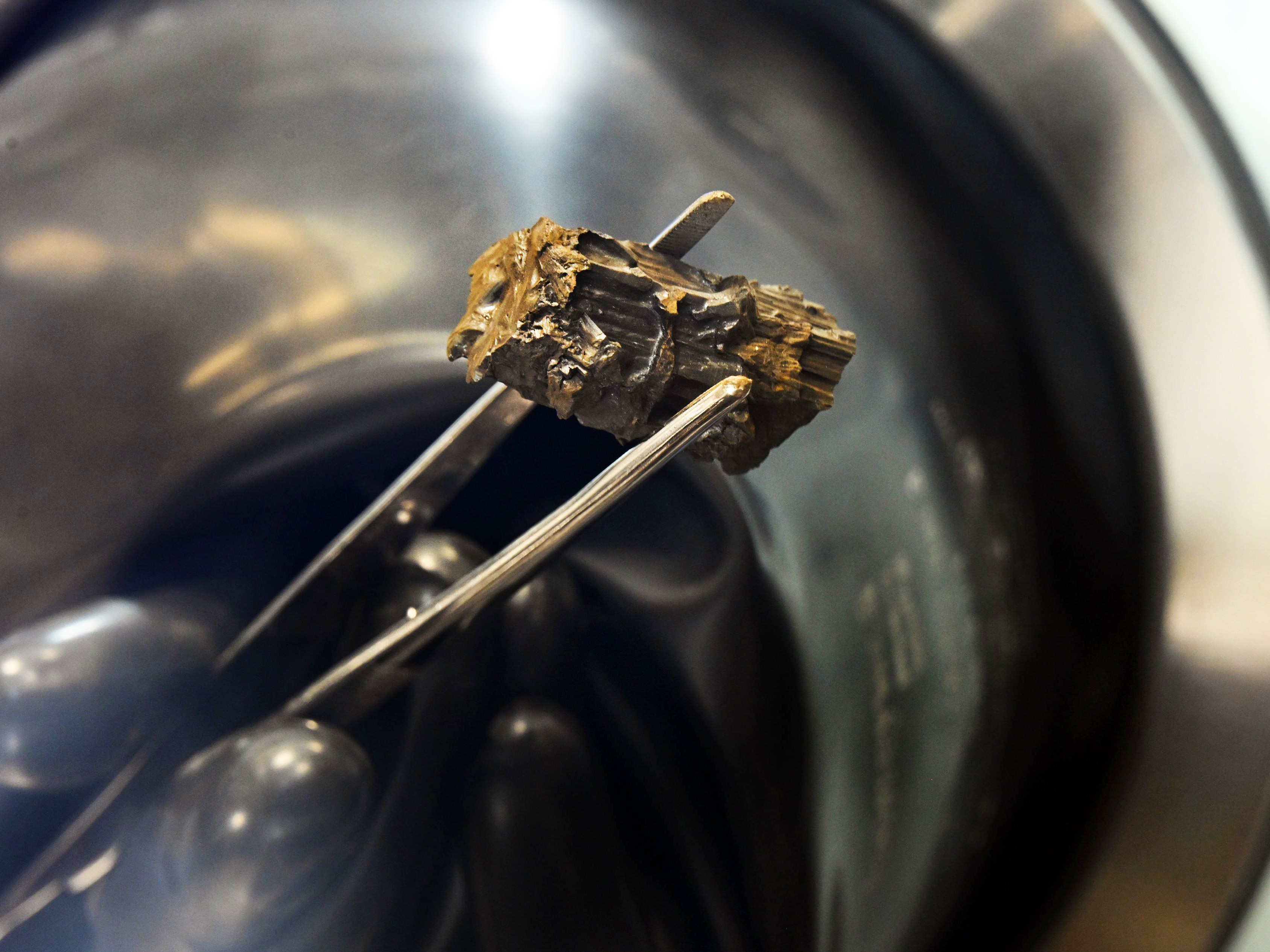 silver tweezers holding gray fuel salt