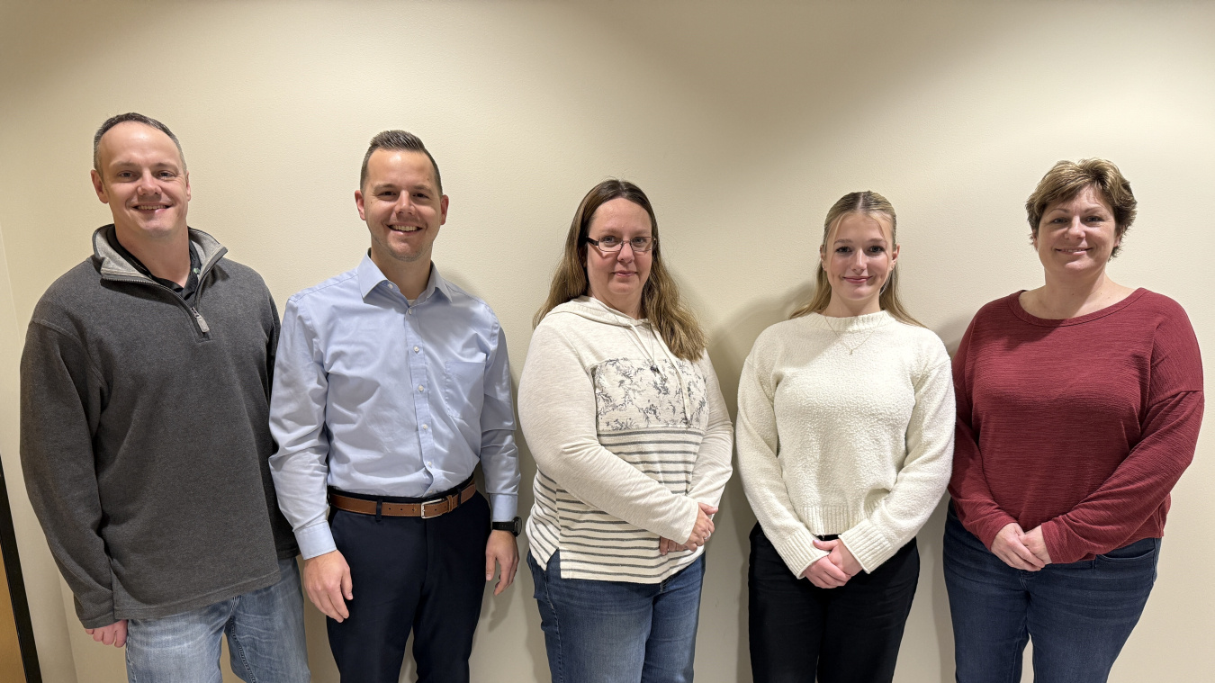 A group of five employees smile for a group photo